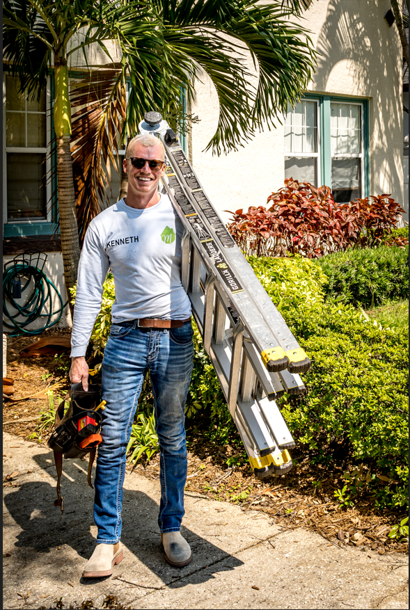 Smiling home inspector carrying ladder and tools